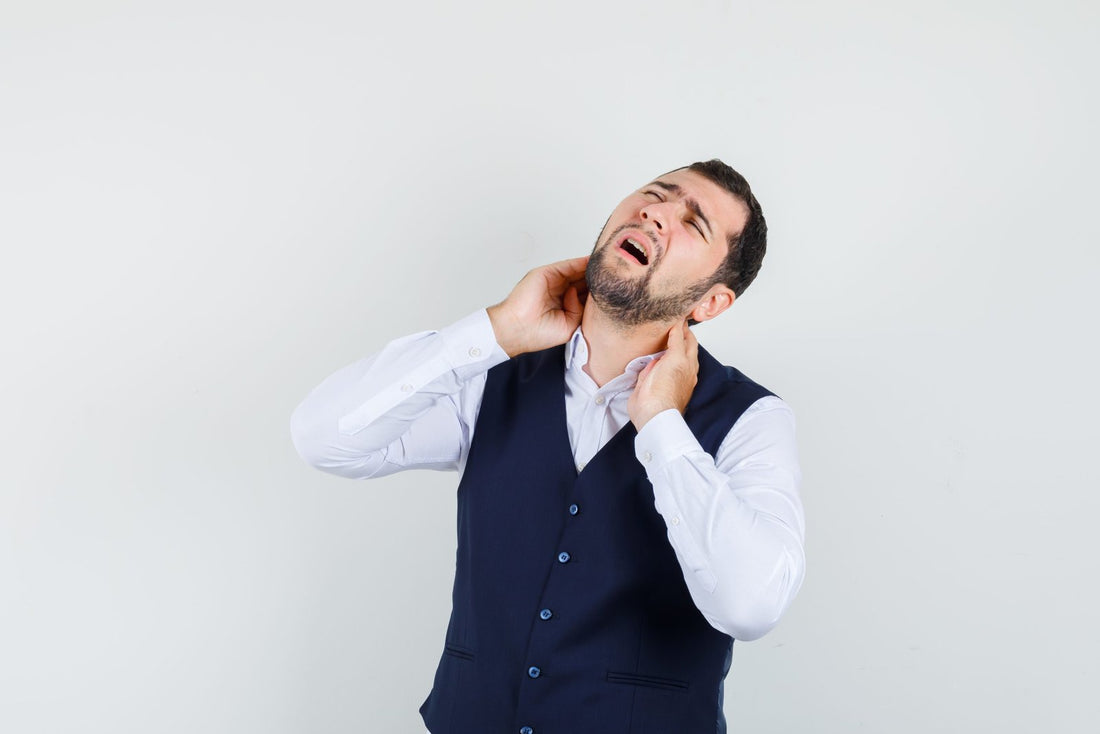 Young man suffering from neck pain in shirt, vest and looking tired. front view.